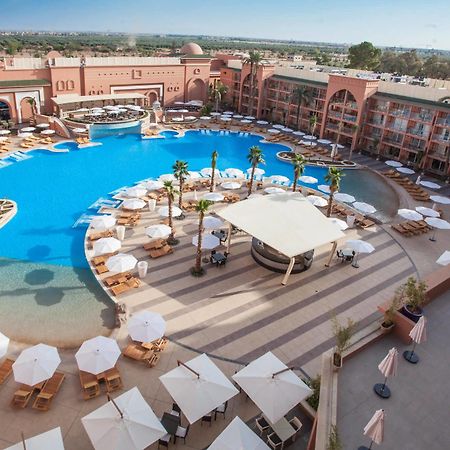 فندق سافوي لي جراند مراكش المظهر الخارجي الصورة The photo shows a large, luxurious hotel resort with a spacious swimming pool at its center. The pool area features several lounge chairs and umbrellas arranged around the water, providing a relaxing atmosphere for guests. Surrounding the pool are la